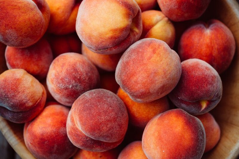 A group of ripe peaches in a bowl.