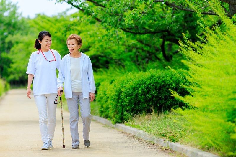 Elderly women and caregivers walking.