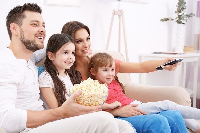 Family watching TV on sofa at home