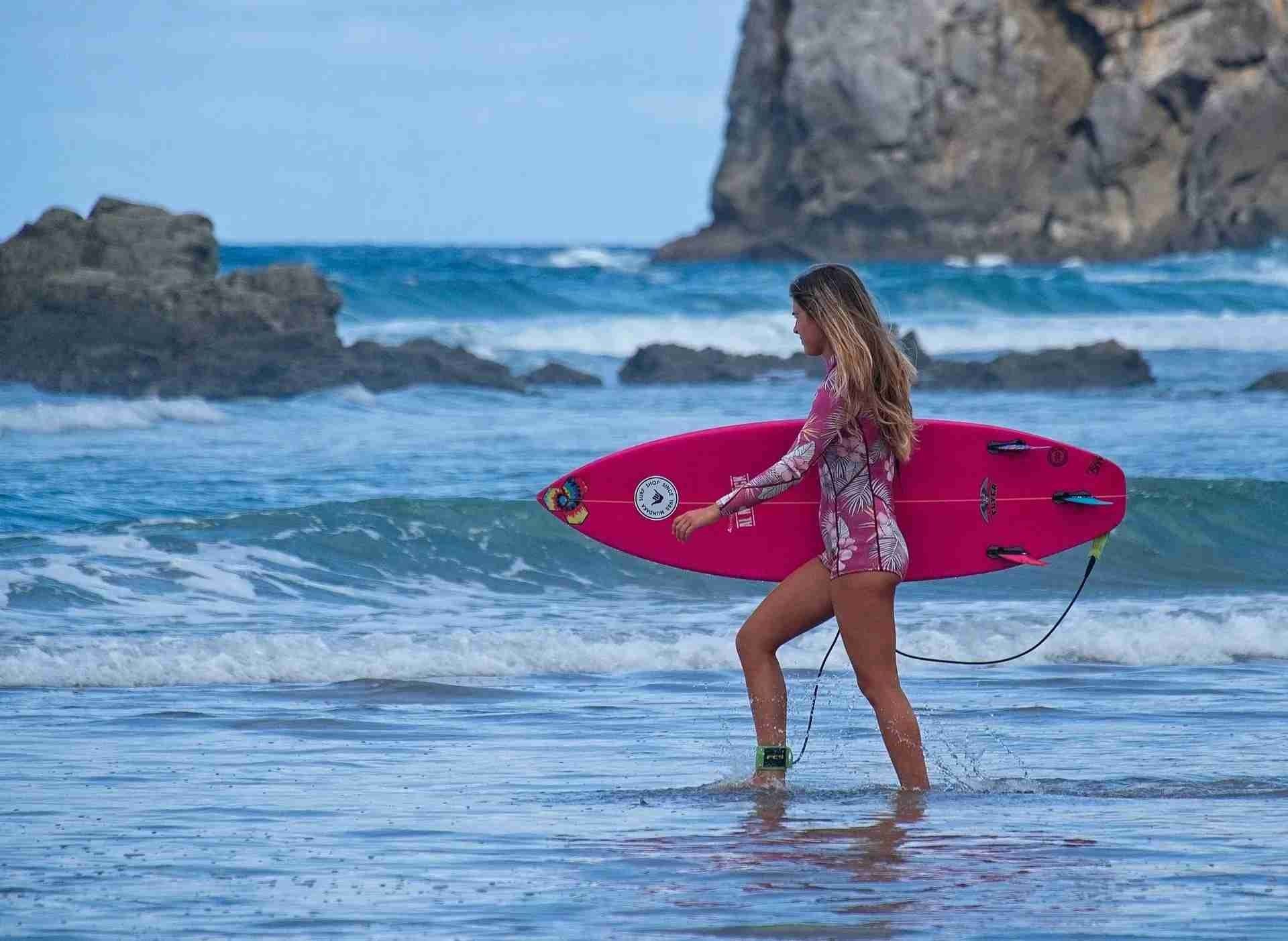 A girl carrying a surfboard on beach