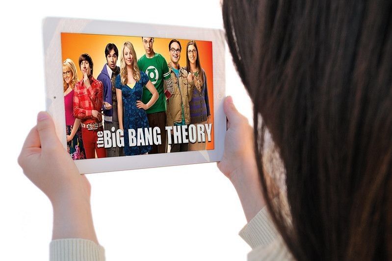 A  woman watching The Big Bang Theory on her Ipad, 