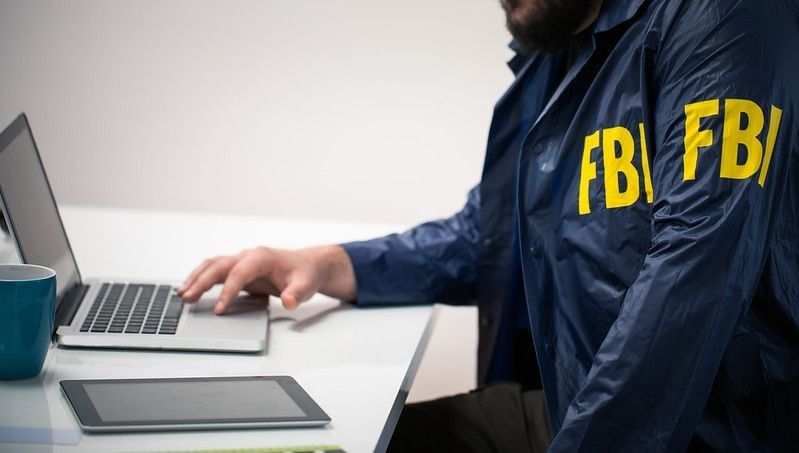 Young FBI agent uniform office using laptop.
