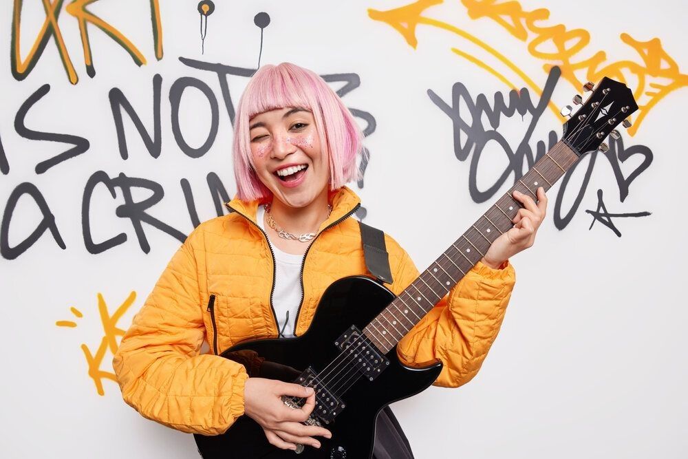 Positive female teenage rocker plays electric guitar