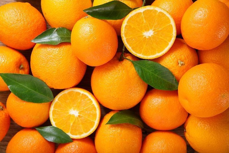 Fresh orange fruits with leaves as background.