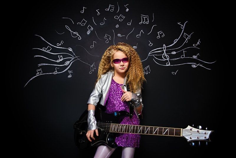A girl holding a black electric guitar