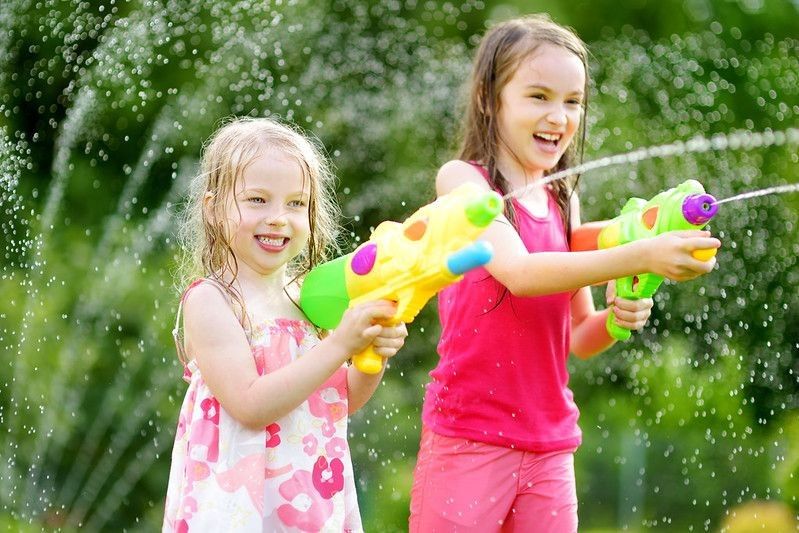 Adorable girls playing with water gun