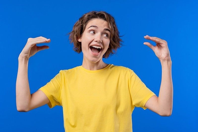 Funny woman showing bla-bla-bla gesture with hands on blue background.