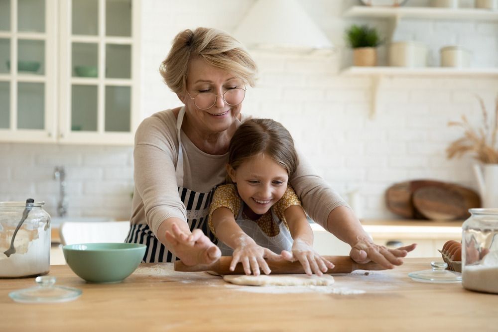 Active aged grandma involve small grandkid girl in rolling yeast cookie dough