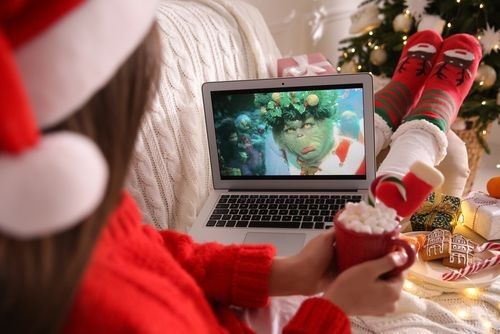 A girl watching Grinch movie on laptop while enjoying a cup of marshmellows.