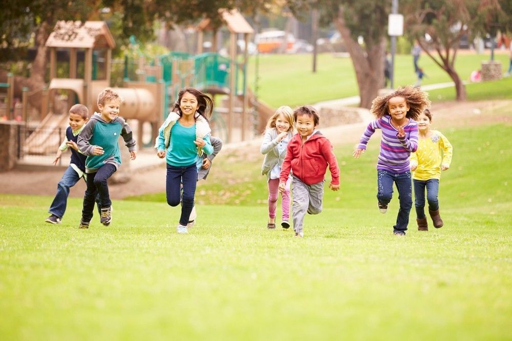 Group Of Young Children Running Towards Camera In Park.