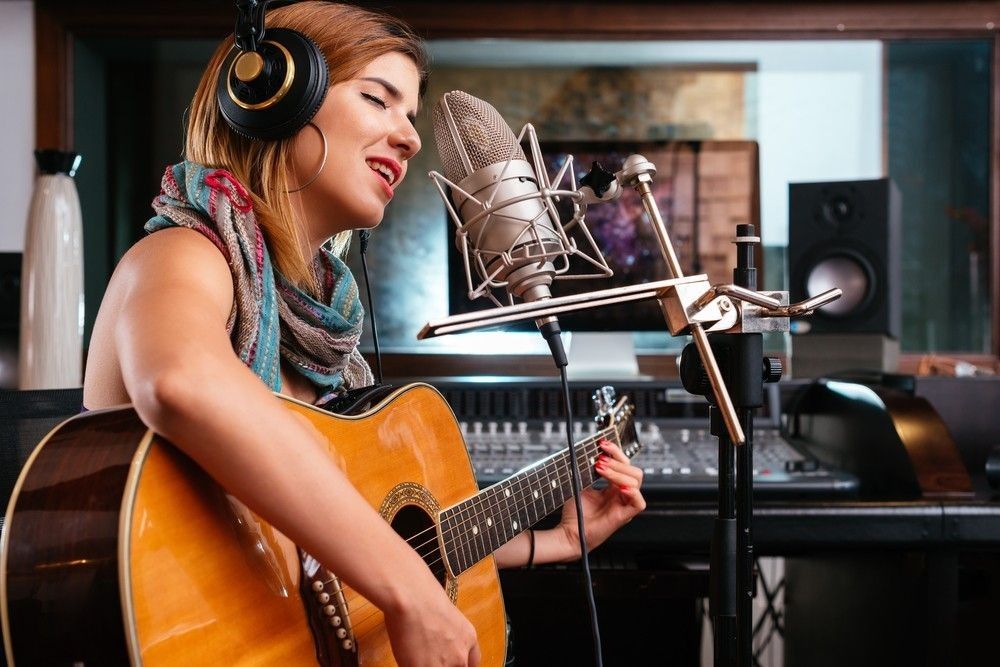 Young woman with guitar recording
