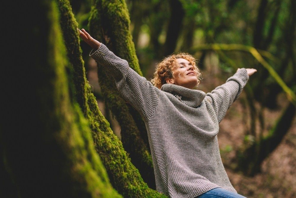 Overjoyed happy woman enjoying the green beautiful nature woods forest around her.