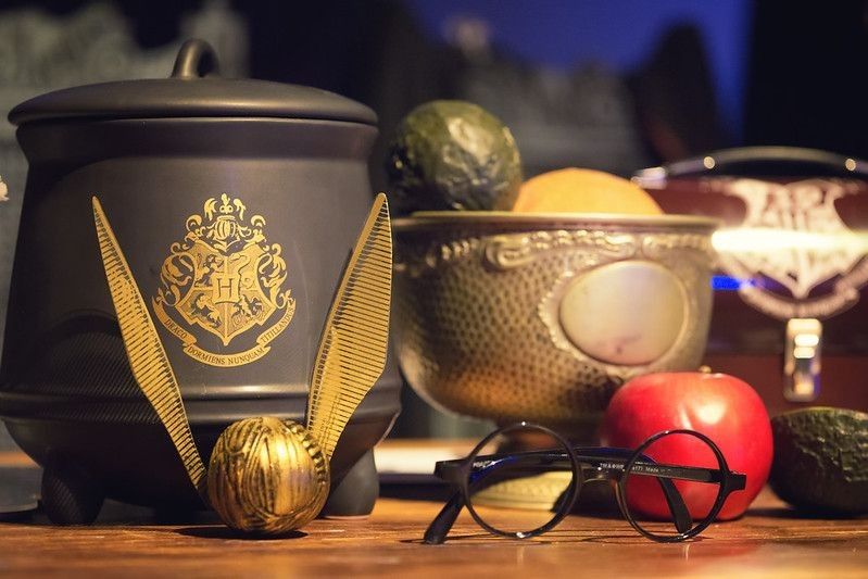 Display of Harry Potter related objects : glasses, quidditch ball and pot.