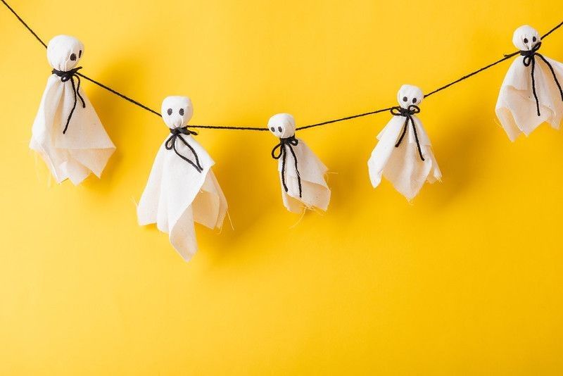 Spooky ghost decorations on yellow wall for Halloween