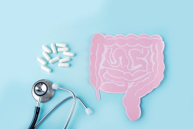 Stethoscope, medicines and illustrative human intestine cut-out on a blue table