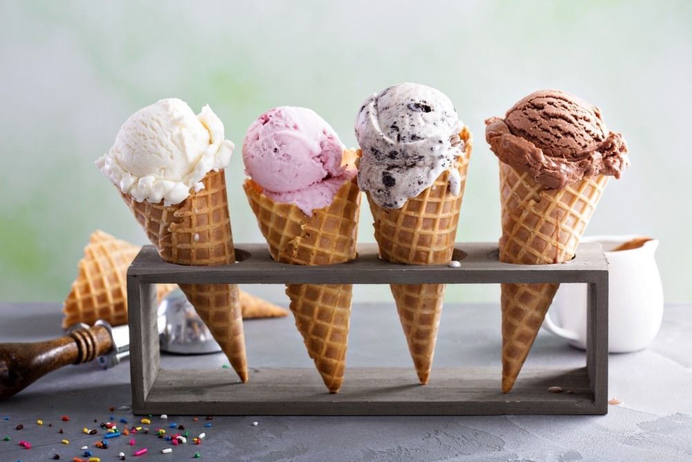 Variety of ice cream scoops in cones with chocolate, vanilla and strawberry.