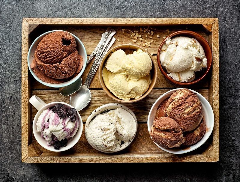 Bowls of various ice creams on dark gray table.