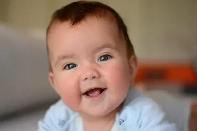 A cute baby with blue eyes smiling at the camera