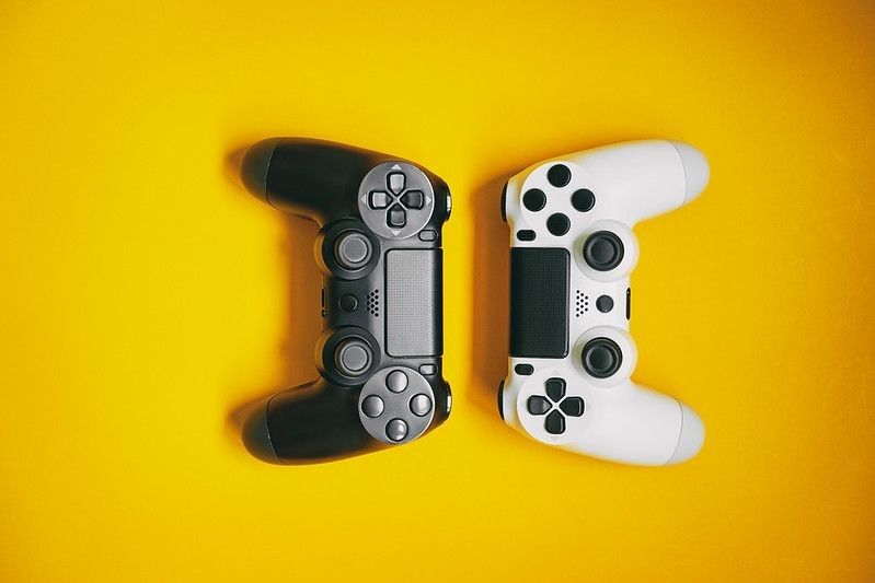 White and black video game controllers on yellow background.