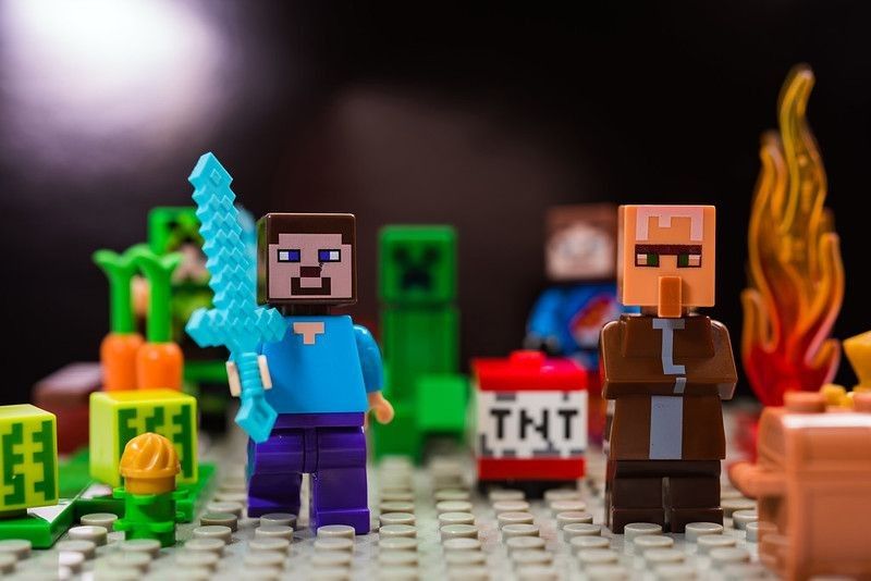 Minifigure Steve with diamond sword and villager run away from the Creeper. Characters of the game Minecraft.