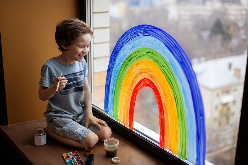 Child at home draws a rainbow on the window.