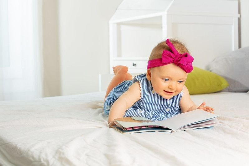 Portrait of little stylish baby girl read book