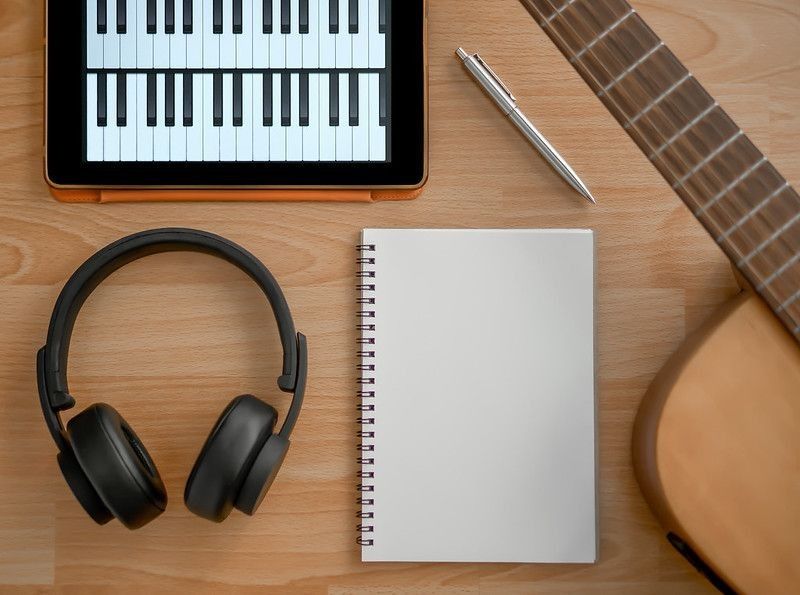 Songwriting Tools, Headphone, Guitar, Notebook, Electronic Tablet and Pen on Wooden Background Top View