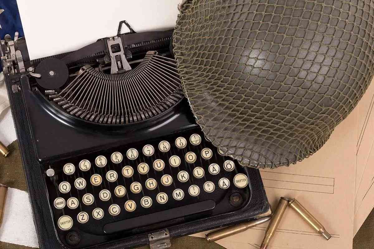 An old-fashioned typewriter with a helmet perched next to it.