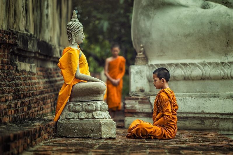Monk meditating in front of Buddha statue