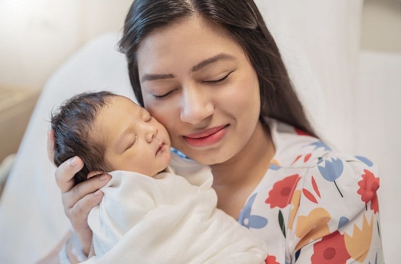 Closeup portrait of young asian Indian mother holding newborn baby