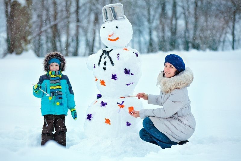 Mother and her little son painting a snowman.