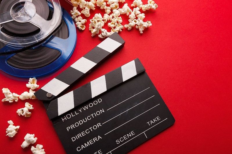 Clapperboard and popcorns with reel on table