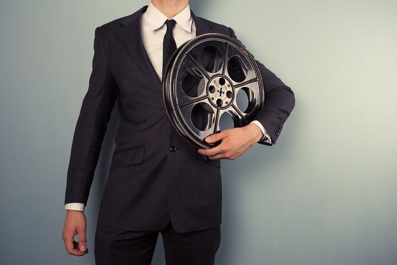 A young movie executive is holding an old film reel