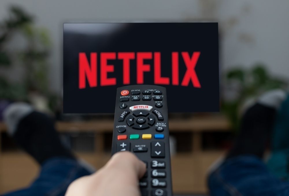 Television Netflix logo on screen with remote control in home.
