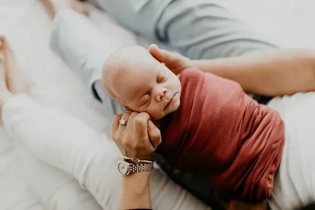 A newborn baby sleeping in it's parents arms