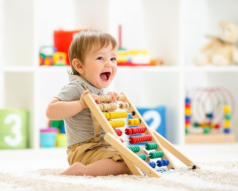 Happy baby boy playing with toy abacus.