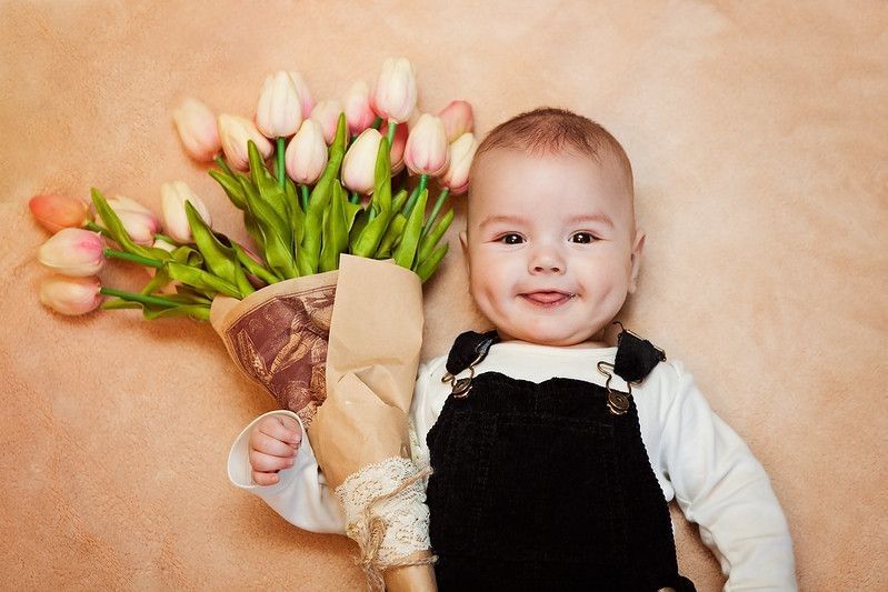 Baby boy holding orange pastel tulip bouquet.