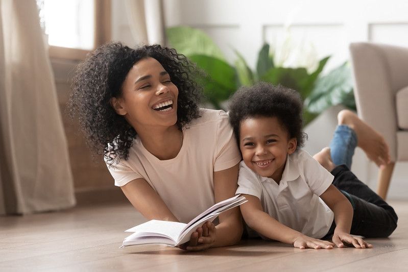 Mother and son laughing while reading a book