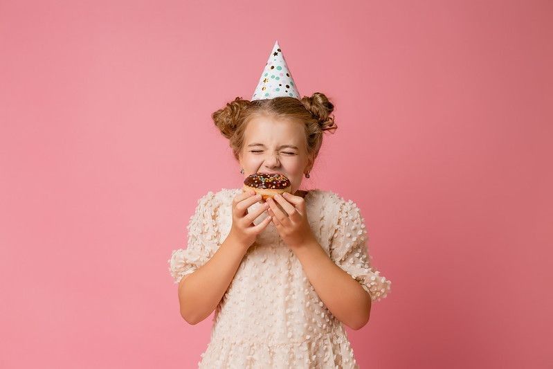 Happy young girl eating donut on her birthday
