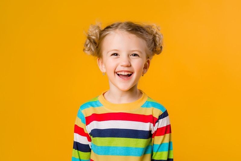 Happy young girl smiling against yellow background
