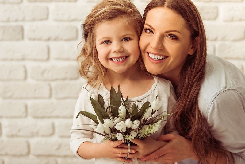 Happy mother and daughter holding flower bouquet