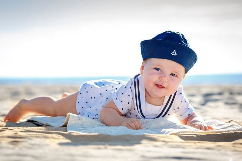Portrait of a cute newborn baby lying on stomach on tropical beach