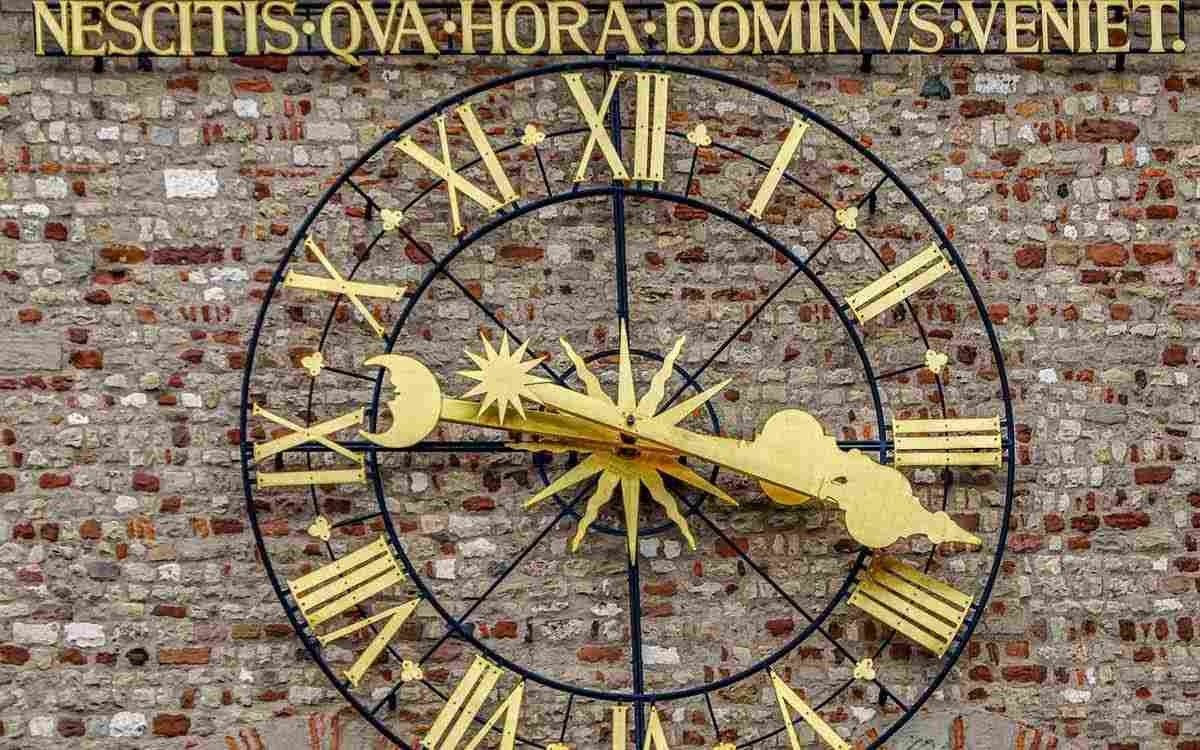 A large, ornate, gold clock face which uses Roman numerals.