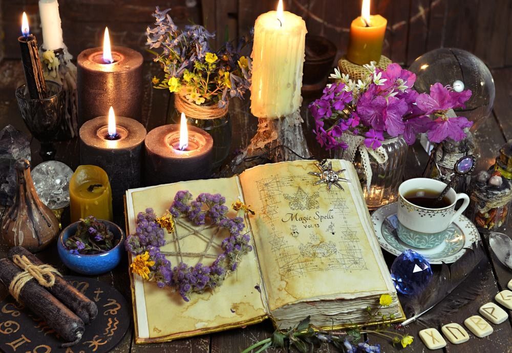 Open witch book with spells, black candles and cup of coffee.