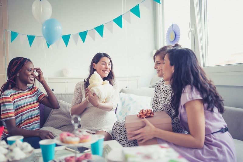 Four smiling ladies having a baby shower party in a beautifully decorated room