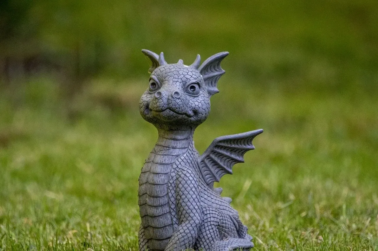 A cute baby dragon stone sculpture on green grass