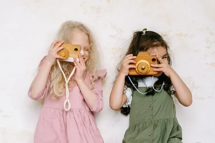 Two girls posing with wooden cameras