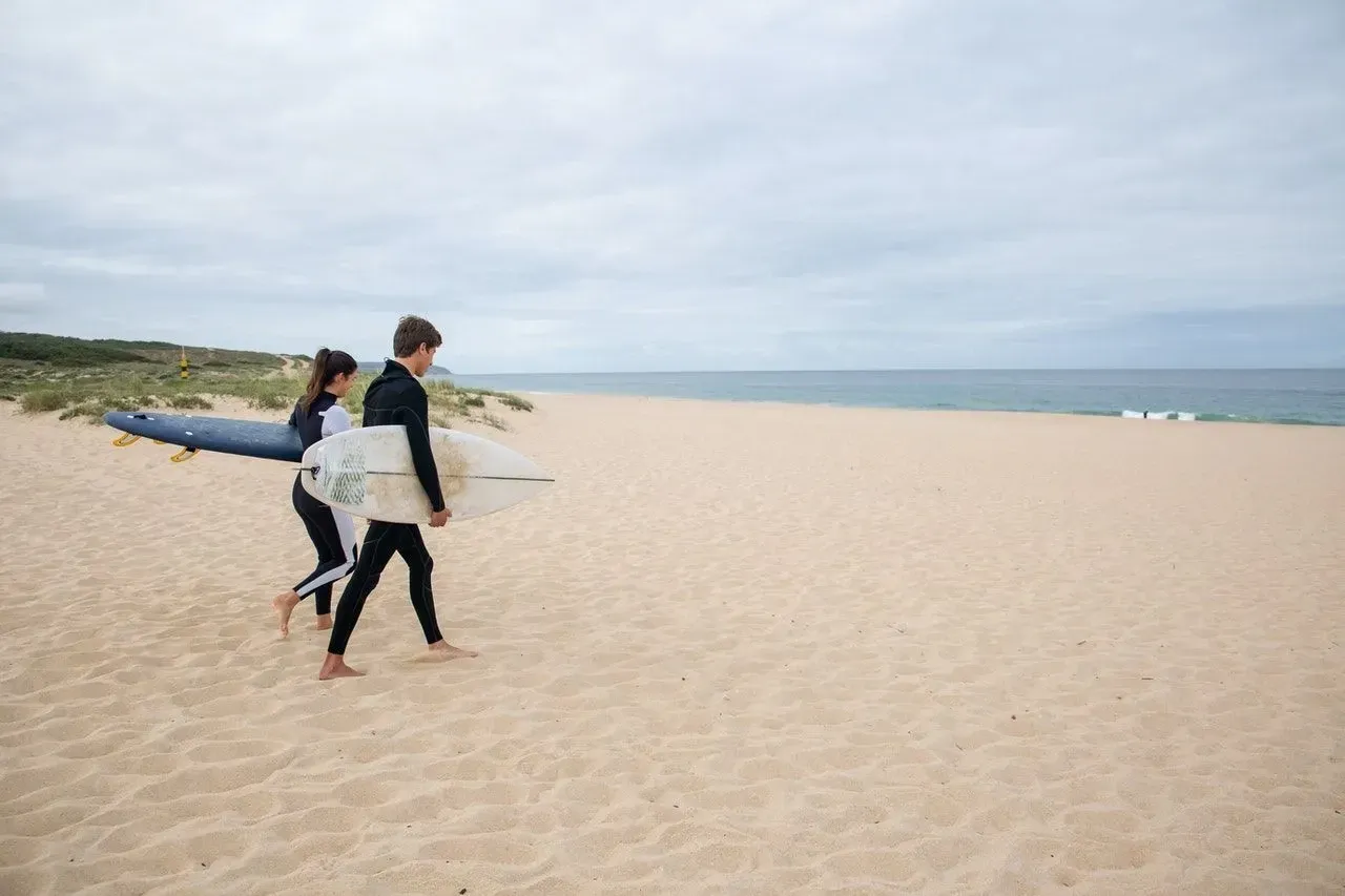 Two surfers walking with surfboards on a beach