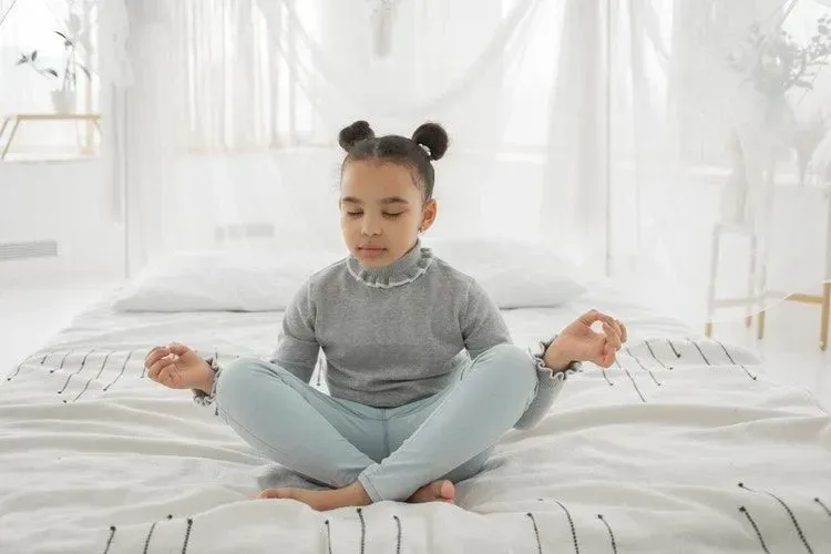 A young girl meditating in her bedroom