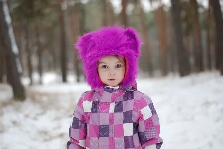 A girl wearing pink and purple winter clothes in snow